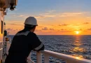 Моряк на борда на търговски кораб по залез слънце – умората на моряците и морската безопасност.
